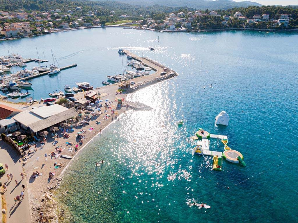Aerial view of Freestyle Windsurf Center in Lumbarda, Korčula, showing the beach, bay, and part of the town